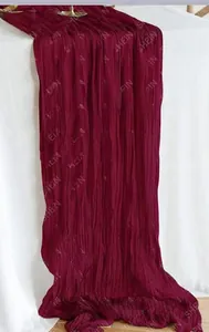 Detailed texture of burgundy pleated table runner in wrinkled semi-transparent fabric