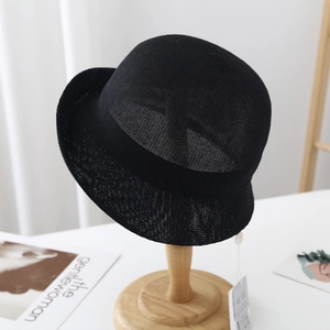 Detail of black breathable knit straw hat featuring elegant woven texture and side tag