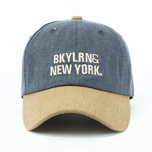 Close-up of embroidered letters on washed denim and khaki contrast baseball cap
