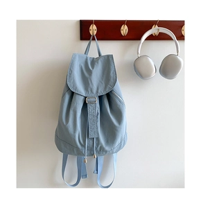 Zaino in nylon azzurro appeso con cuffie argentate in un ambiente di vita quotidiana