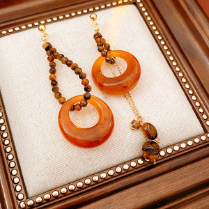 Detail of asymmetrical vintage resin earrings with tiger eye beads and gold metal chains
