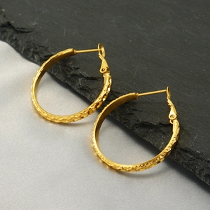 Detailed close-up of gold stainless steel hoop earrings with textured diamond-cut facets