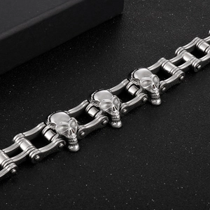 Detailed macro of silver stainless steel skull bike chain bracelet on black background