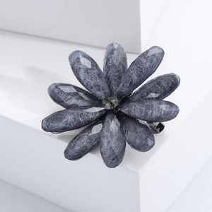 Detail of grey acrylic flower brooch with brushed texture petals and crystal center