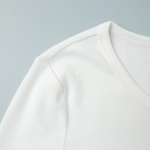 Detail of white ribbed knit fabric featuring a round neck and reinforced stitching