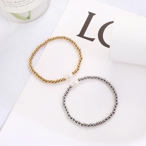 Detail of 4mm gold and silver beads with a white freshwater pearl on an elastic bracelet