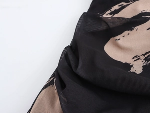 Détail du tissu en maille noire et beige avec texture drapée et froncée