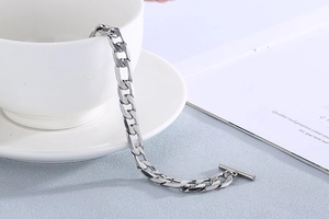 Bracelet à mailles cubaines en acier argenté avec fermoir à bascule sur une tasse