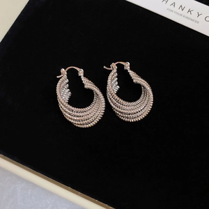Detailed view of silver hollow twisted oval hoop earrings on black velvet background