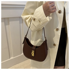 Dettaglio borsa a mezzaluna marrone scuro con fibbia dorata su un trench beige