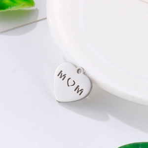 Polished heart-shaped MOM pendant made of stainless steel on white surface