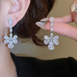 Detailed macro view of silver floral drop earrings with sparkling zircon tassels