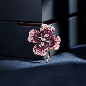 Elegant gold clover brooch with sparkling purple crystals on dark fabric background