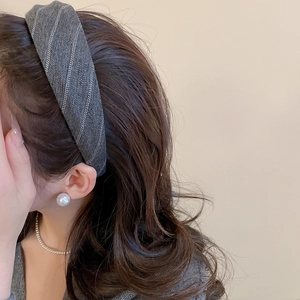 Detail of grey herringbone fabric headband styled with elegant pearl accessories on a model