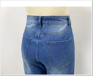 Detail van achterzakken en gouden contraststiksels op jeans met een hoge taille