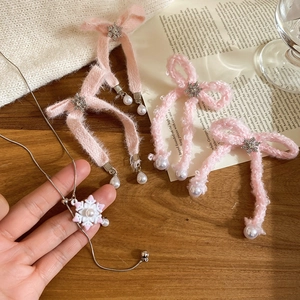 Detail of pink bow pearl earrings and snowflake necklace with plush texture