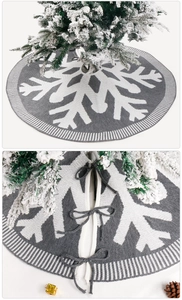 Detail of grey knitted Christmas tree skirt featuring white snowflake patterns and tie closure