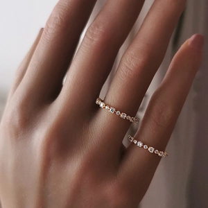 Dettaglio di due anelli a fascia in oro rosa con zirconi micro-pavé su una mano