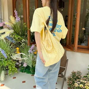 Détail du sac fourre-tout en toile jaune à bulles évidées avec motif rayé en extérieur