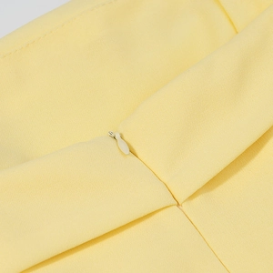 Détail de la fermeture éclair invisible sur le tissu tissé jaune clair de la robe