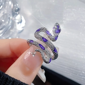 Vintage silver snake wrap ring with purple gemstones shown on finger in macro view