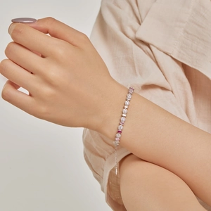 Close-up of S925 silver tennis bracelet with pink and red zircon stones on woman's wrist