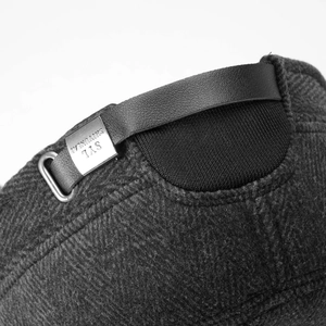 Detail of adjustable leather strap and brand metal buckle on grey winter baseball hat