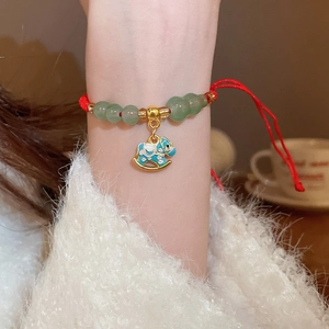 Détail du bracelet tressé rouge avec perles de jade vert et pendentif cheval bleu