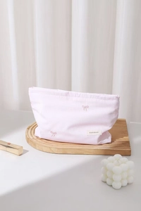 Détail de broderie nœud rose sur la trousse de maquillage souple en polyester rose