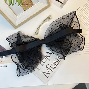 Close-up of black polka dot mesh bow hair clip with vintage lace on a fashion magazine
