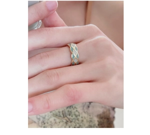 Detail showing gold ring with light green enamel lattice pattern and pearl accents