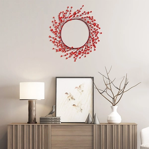 Christmas red berry wreath hanging on a white wall above a wooden cabinet for home decor
