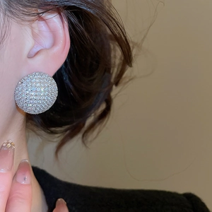 Gros plan de boucles d'oreilles rondes pavées de zircons portées par un mannequin