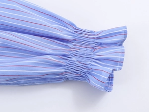 Détail de poignets froncés à volants sur une chemise à rayures bleues et blanches