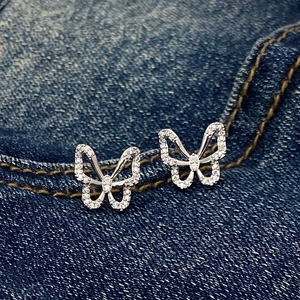 Close-up of silver butterfly stud earrings with sparkling pave-set stones on denim background