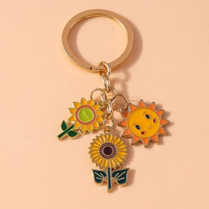 Macro shot of sunflower and happy sun charms on a golden alloy keyring with enamel finish
