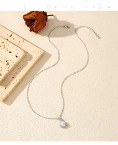 Artistic detail of a pear-cut moissanite pendant necklace with silver chain and dried rose