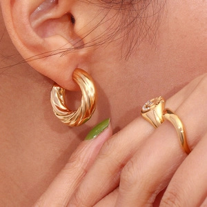 Macro shot of 18K gold plated twisted rope texture C-shape earrings on a model