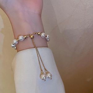 Detailed view of an adjustable pearl bead bracelet with gold accents and drawstring clasp