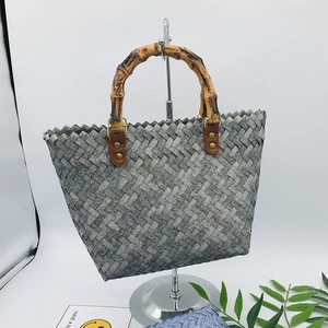 Detail of gray woven tote bag featuring a vintage bamboo handle and metal rings