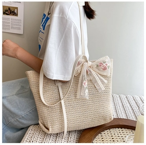 Detail of summer straw tote bag with lace bow decoration and floral embroidery