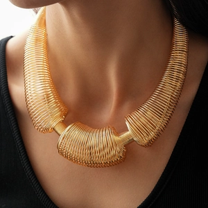 Close-up of a gold spring coil statement necklace on a model wearing black ribbed top