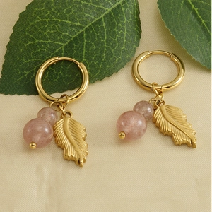Detail of 18k gold earrings with pink natural stone beads and feather charms