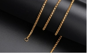 Macro shot of polished gold box chain link showing metallic luster on a black display