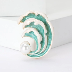 Détail de la broche vague en émail bleu avec perle blanche et finition dorée