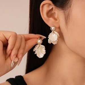 Detailed close-up of golden pearl flower earrings with multi-layered shell petals