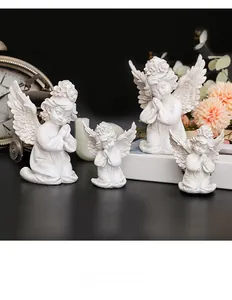 Detail of four white cherub statues praying next to a Kinfolk book and orange flowers