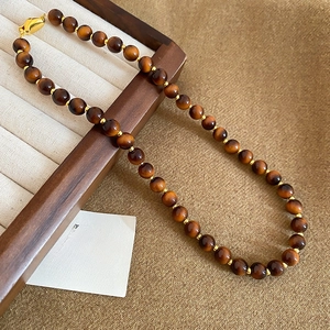 Macro shot of tiger eye bead necklace with gold spacers and lobster clasp detail