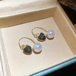 Détail de boucles d'oreilles avec cristal de cœur gris et perle dans un écrin