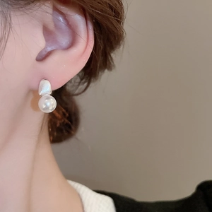 Close-up of minimalist irregular pearl earrings with silver geometric accents on model